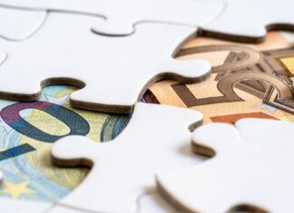 Banknoty euro widoczne spod puzzli symbolizujących rozwiązania finansowe