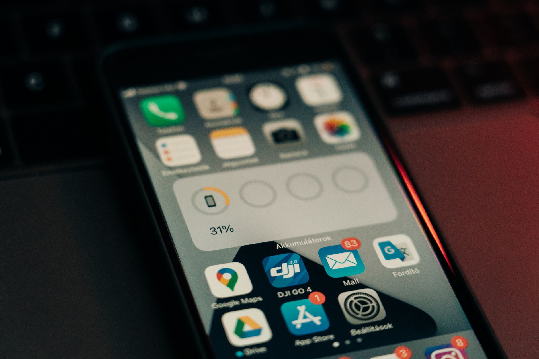 Smartfon z ikonami aplikacji leżący na klawiaturze, widoczny stan baterii 31%